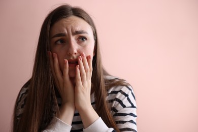 Photo of Scared woman suffering from paranoia near beige wall indoors, space for text