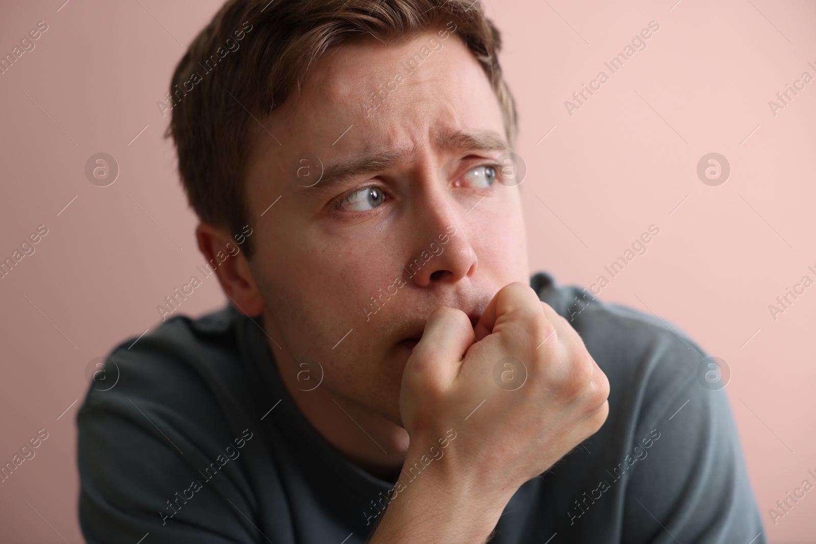 Scared man suffering from paranoia near beige wall indoors Photo of Scared man suffering from paranoia near beige wall indoors