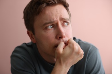 Photo of Scared man suffering from paranoia near beige wall indoors