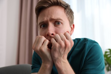 Photo of Scared man suffering from paranoia at home
