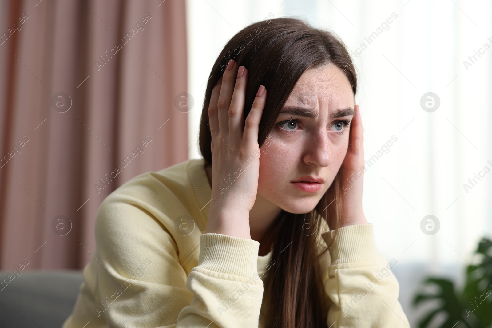 Scared woman suffering from paranoia at home Photo of Scared woman suffering from paranoia at home