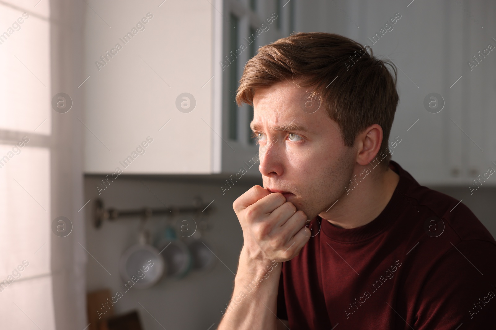 Man suffering from paranoia in kitchen, space for text Photo of Man suffering from paranoia in kitchen, space for text