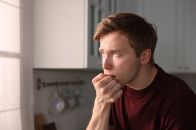 Photo of Man suffering from paranoia in kitchen, space for text
