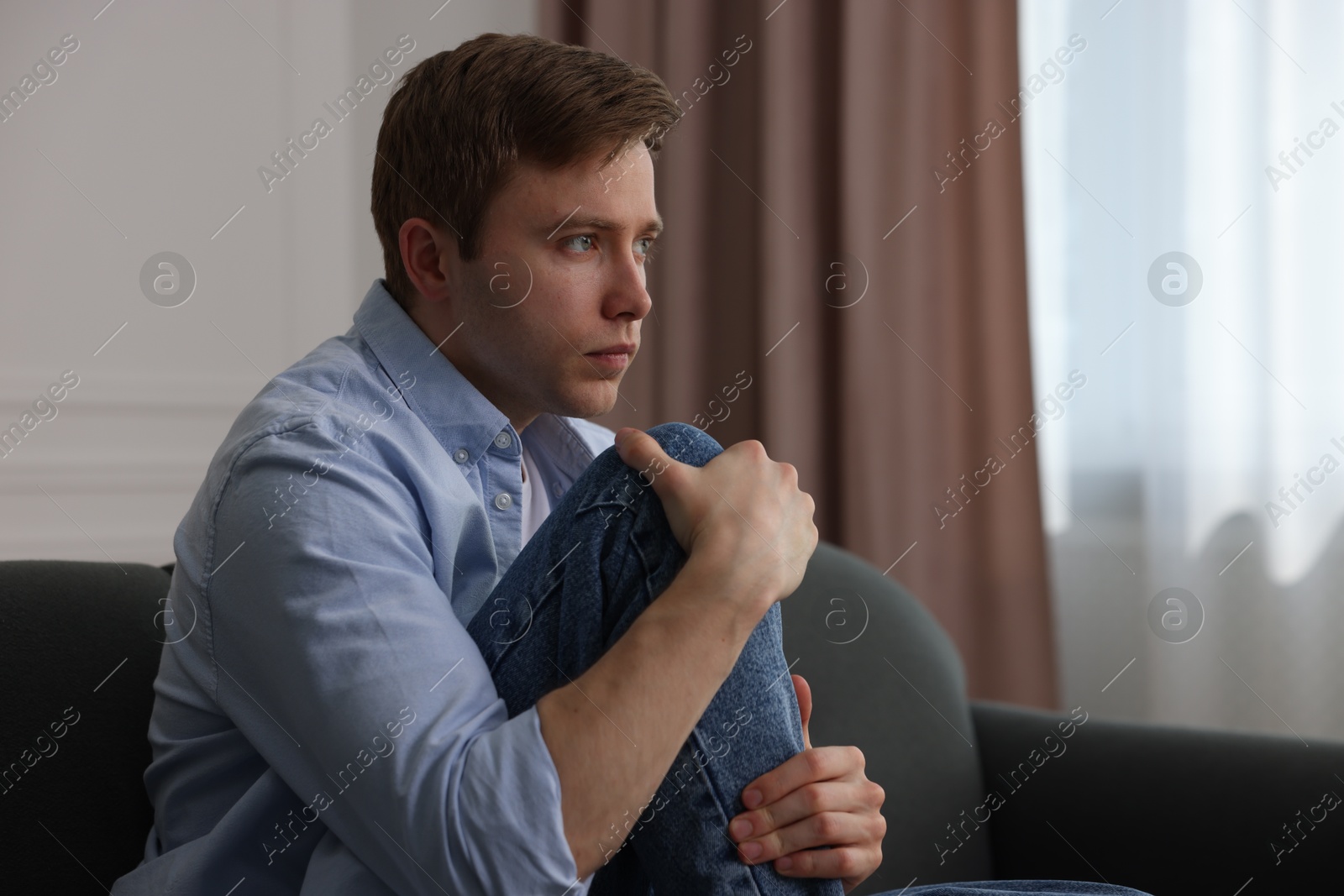 Man suffering from paranoia on sofa at home, space for text Photo of Man suffering from paranoia on sofa at home, space for text