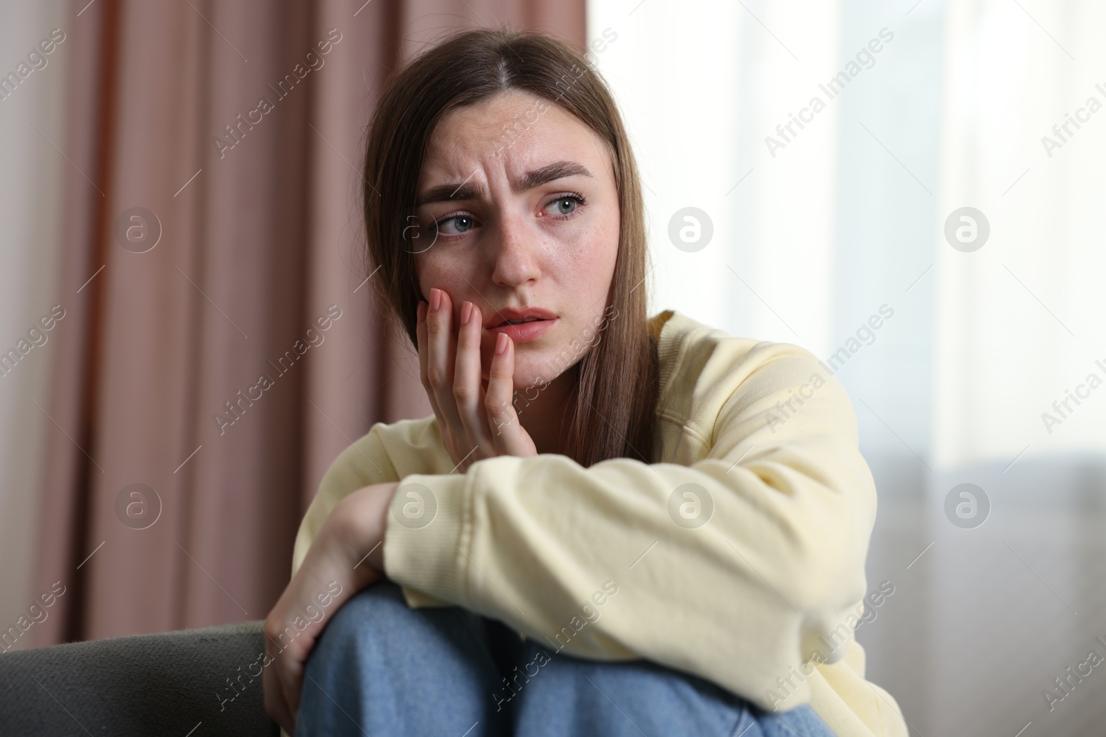 Scared woman suffering from paranoia at home Photo of Scared woman suffering from paranoia at home