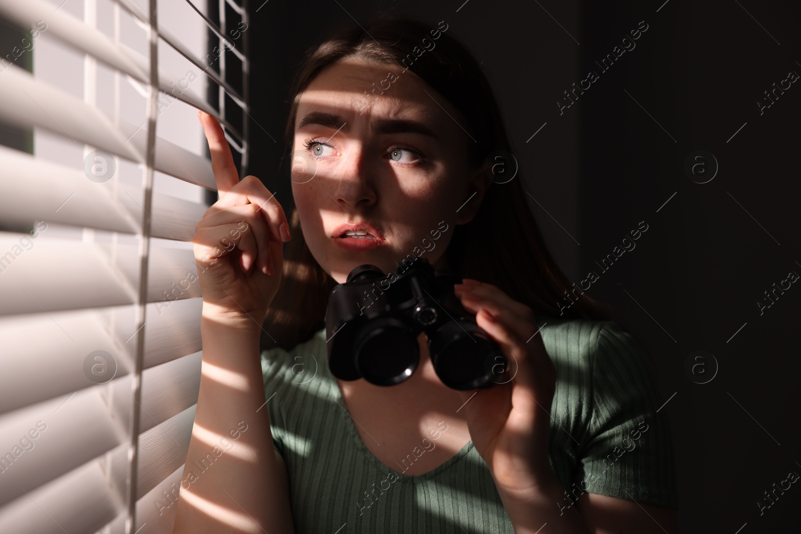 Paranoia. Worried woman with binoculars near window indoors Photo of Paranoia. Worried woman with binoculars near window indoors