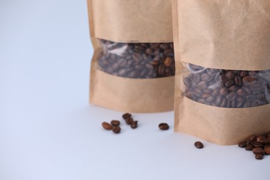 Photo of Zipper stand-up pouches with coffee beans on light grey background, closeup. Mockup for design
