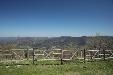 Photo of Picturesque view of wooden fence near mountains and forest