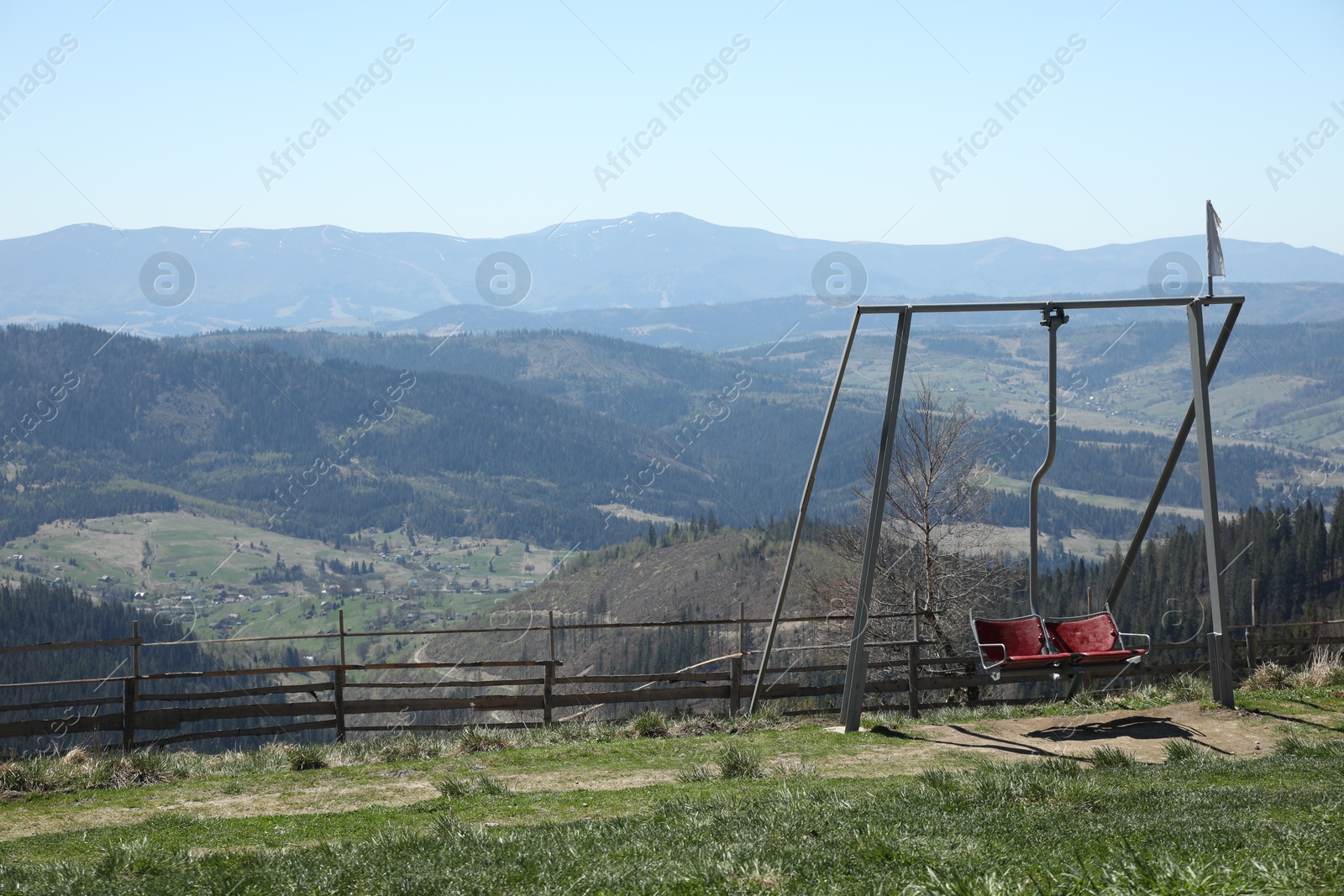 Picturesque view of wooden fence and swing near mountains, space for text Photo of Picturesque view of wooden fence and swing near mountains, space for text