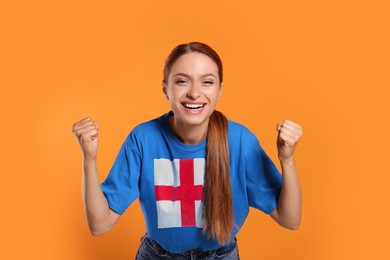 Image of Excited fan with flag of England on her t-shirt against orange background