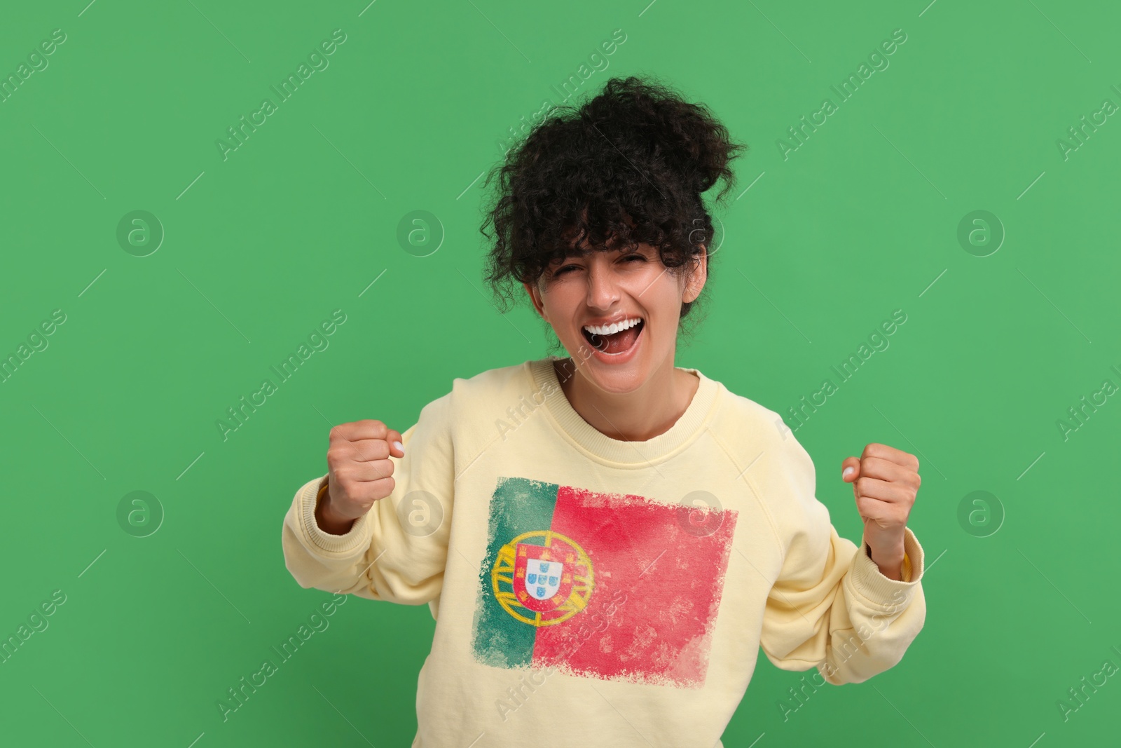 Excited fan with flag of Portugal on her sweater against green background Image of Excited fan with flag of Portugal on her sweater against green background