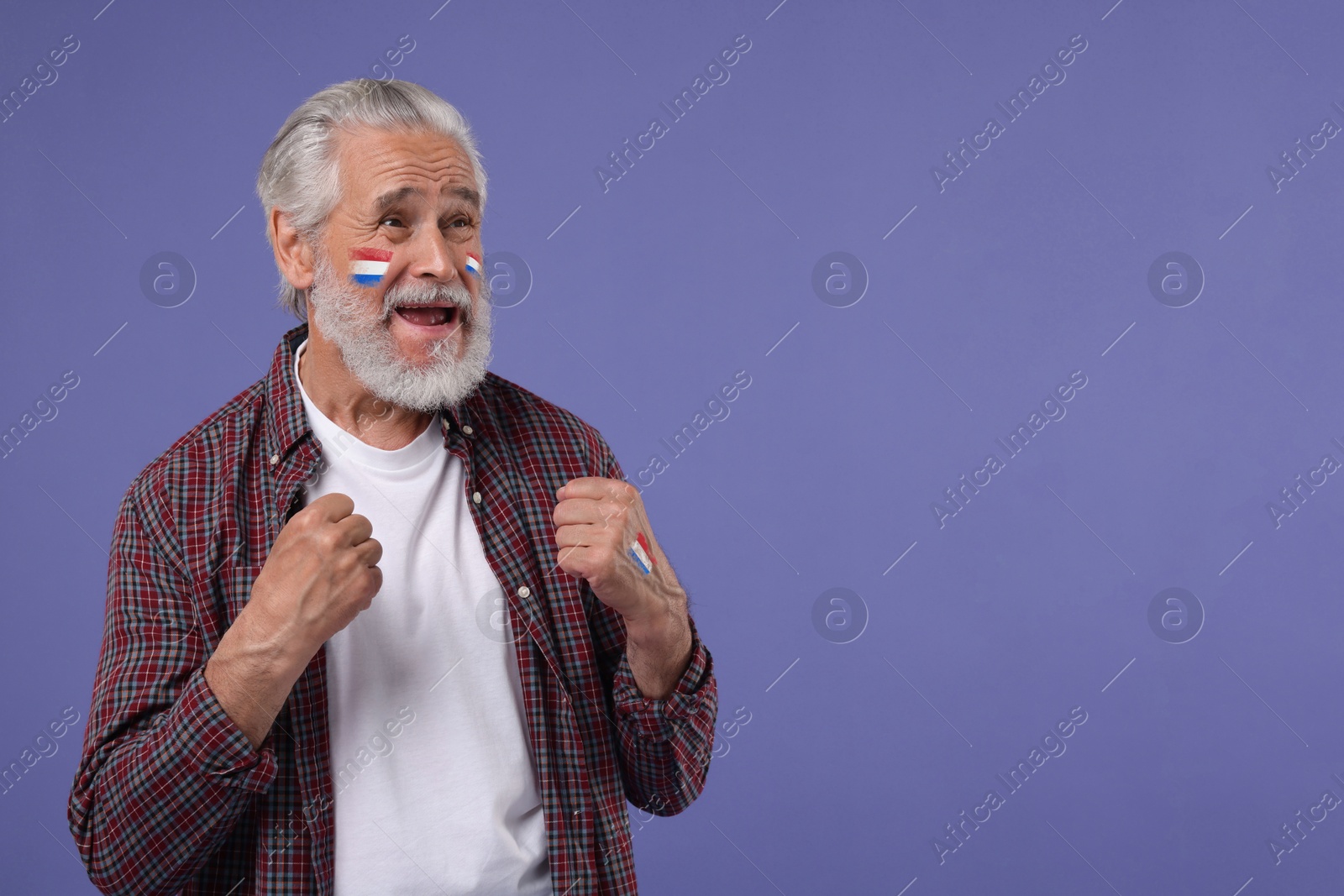 Excited fan with flags of Netherlands painted on his body against dark violet background. Space for text Image of Excited fan with flags of Netherlands painted on his body against dark violet background. Space for text