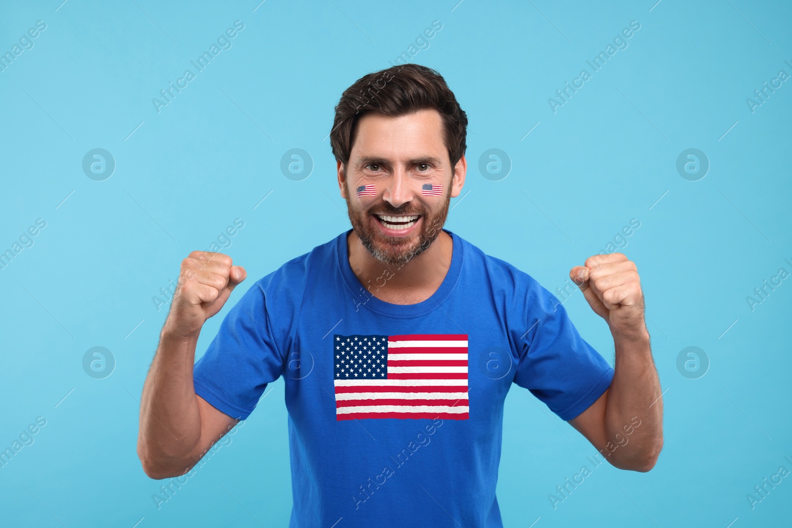 Excited fan with flags of USA on his face and t-shirt against light blue background Image of Excited fan with flags of USA on his face and t-shirt against light blue background