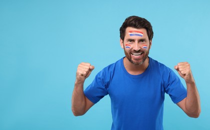Image of Excited fan with flags of Netherlands painted on his face against light blue background. Banner design with space for text