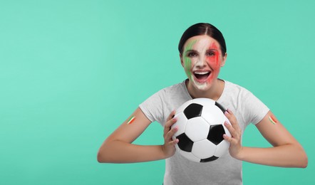 Image of Excited fan with flags of Italy painted on her face and arms holding soccer ball against turquoise background. Banner design with space for text