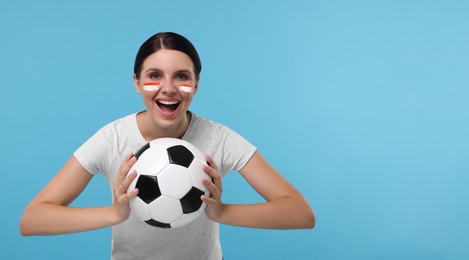 Image of Excited fan with flags of Monaco painted on her face holding soccer ball against light blue background. Banner design with space for text