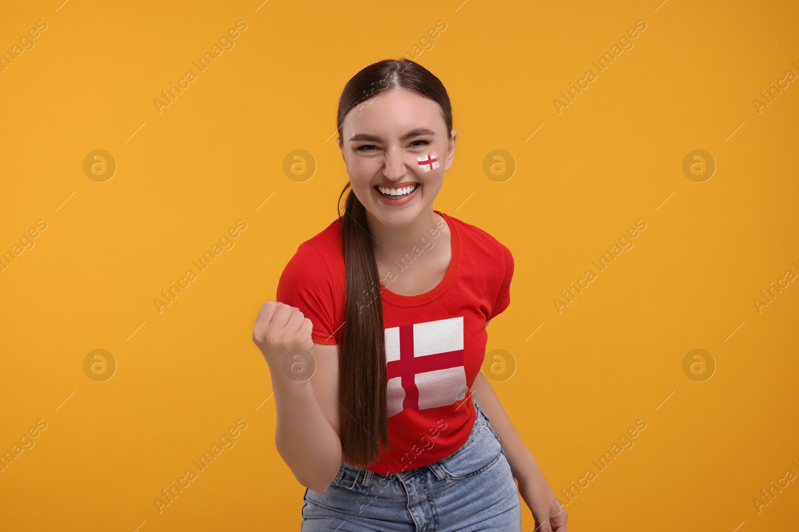Excited fan with flags of England on her face and t-shirt against orange background Image of Excited fan with flags of England on her face and t-shirt against orange background