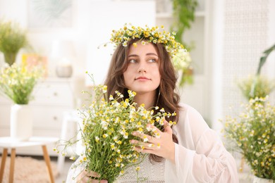 Photo of Portrait of beautiful woman with chamomile flowers indoors