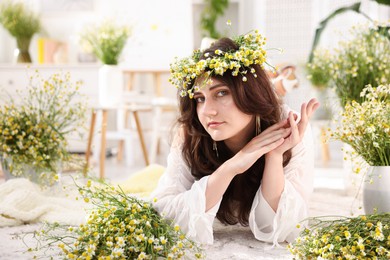 Photo of Beautiful woman with chamomile flowers on floor indoors