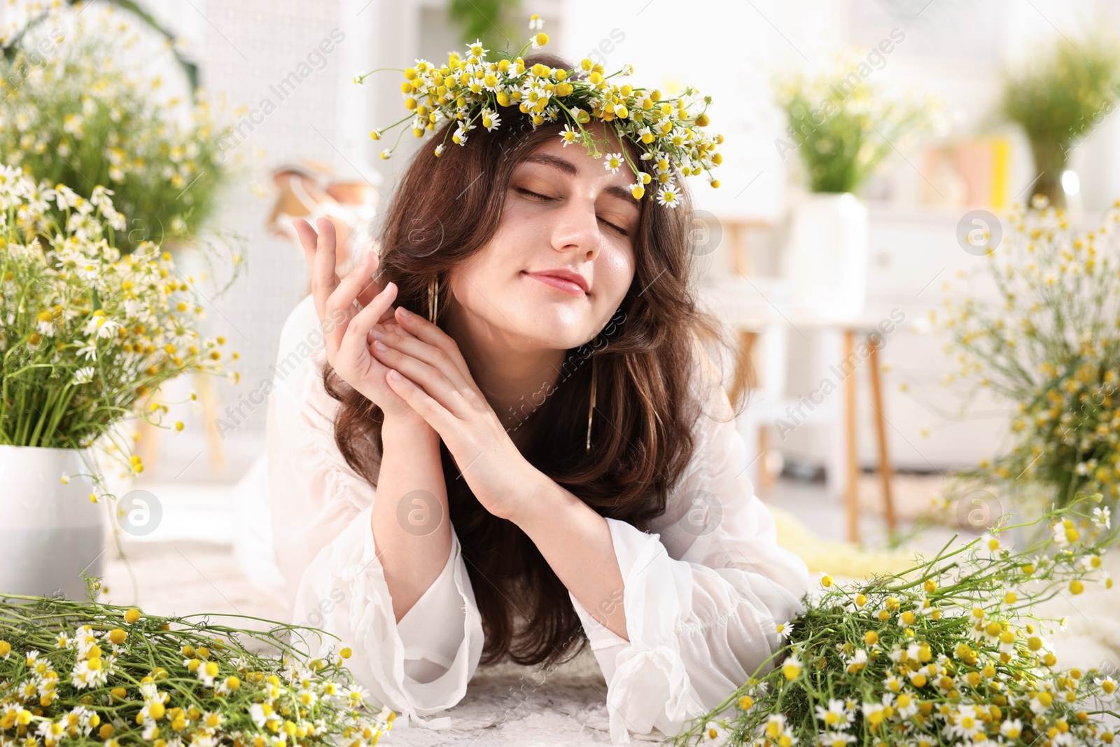 Beautiful woman with chamomile flowers on floor indoors Photo of Beautiful woman with chamomile flowers on floor indoors
