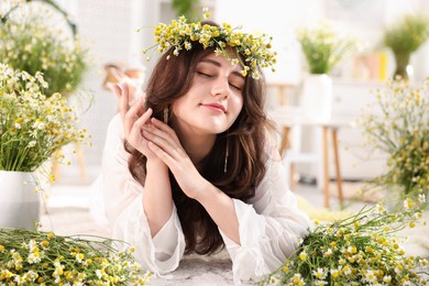 Photo of Beautiful woman with chamomile flowers on floor indoors
