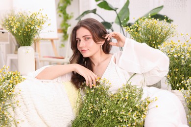 Photo of Portrait of beautiful woman with chamomile flowers indoors