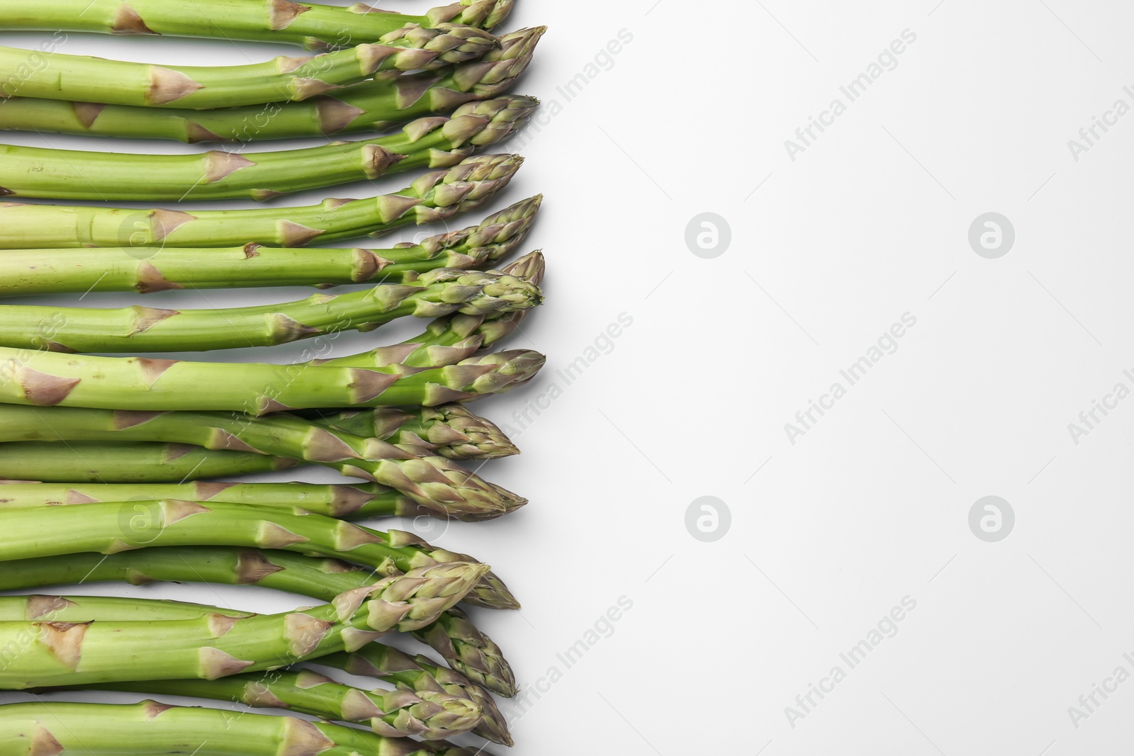 Fresh ripe raw asparagus on white background, flat lay. Space for text Photo of Fresh ripe raw asparagus on white background, flat lay. Space for text