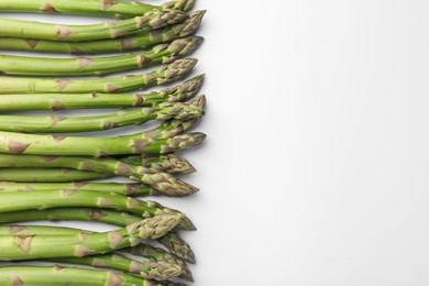 Photo of Fresh ripe raw asparagus on white background, flat lay. Space for text