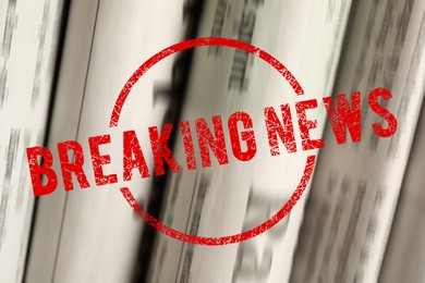 Image of Red Breaking News stamp and newspapers as background, closeup