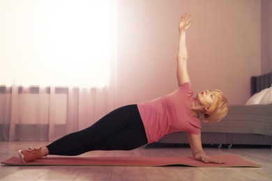 Image of Woman doing side plank exercise on fitness mat at home. Sport and healthy lifestyle