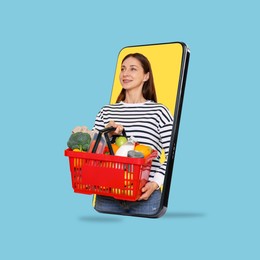 Image of Woman with shopping basket full of products walking out of mobile phone against light blue background. Online ordering