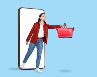 Image of Woman with shopping basket walking out of mobile phone against light blue background. Online ordering