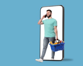 Image of Man with shopping basket full of products walking out of mobile phone against light blue background. Online ordering