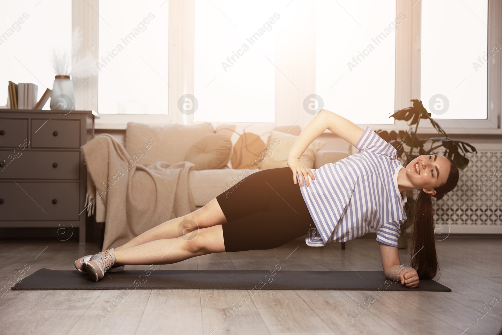Young woman doing side plank exercise on fitness mat at home. Sport and healthy lifestyle Image of Young woman doing side plank exercise on fitness mat at home. Sport and healthy lifestyle