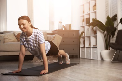 Image of Young woman doing plank exercise on fitness mat at home. Sport and healthy lifestyle