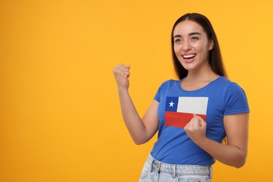 Image of Excited fan with flag of Chile on her t-shirt against orange background. Space for text