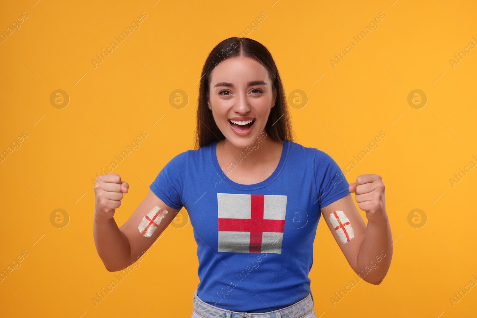 Excited fan with flags of England on her arms and t-shirt against orange background Image of Excited fan with flags of England on her arms and t-shirt against orange background
