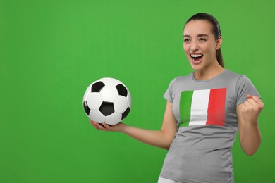 Image of Excited fan with flag of Italy on her t-shirt holding soccer ball against green background. Space for text