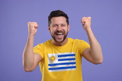 Image of Happy fan with flag of Uruguay on his t-shirt against dark violet background