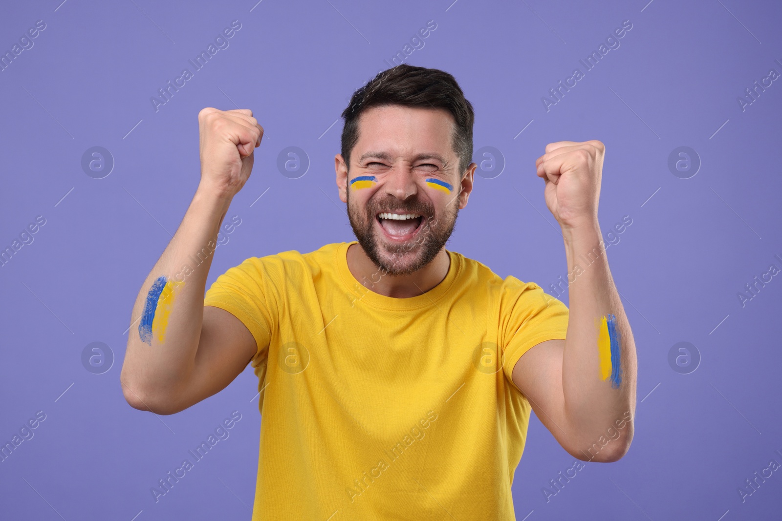 Happy fan with flags of Ukraine painted on his body against dark violet background Image of Happy fan with flags of Ukraine painted on his body against dark violet background