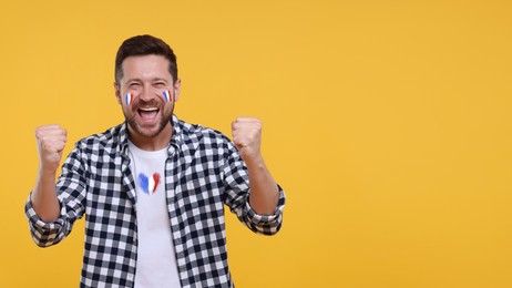 Image of Happy fan with flags of France on his face and t-shirt against orange background. Banner design with space for text