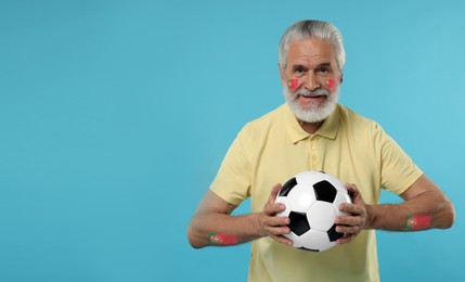 Image of Fan with flags of Portugal painted on his body holding soccer ball against light blue background. Banner design with space for text