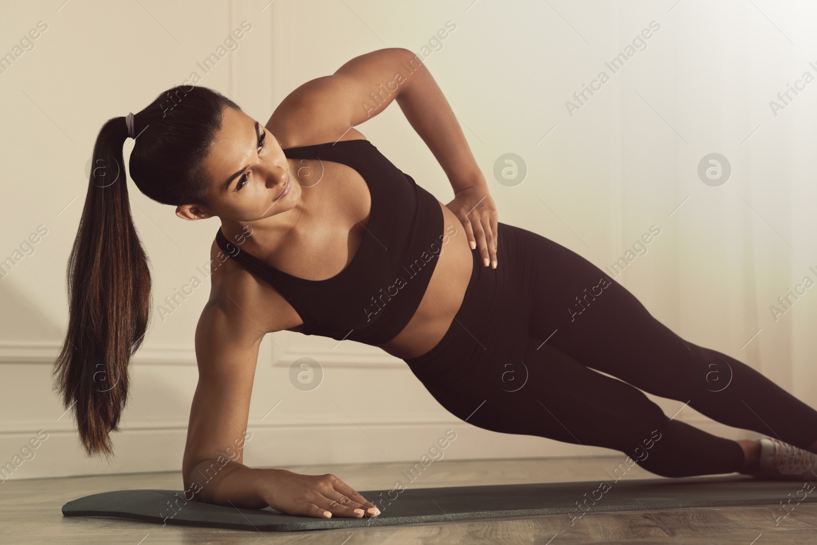 Sporty woman doing side plank exercise on fitness mat indoors Image of Sporty woman doing side plank exercise on fitness mat indoors