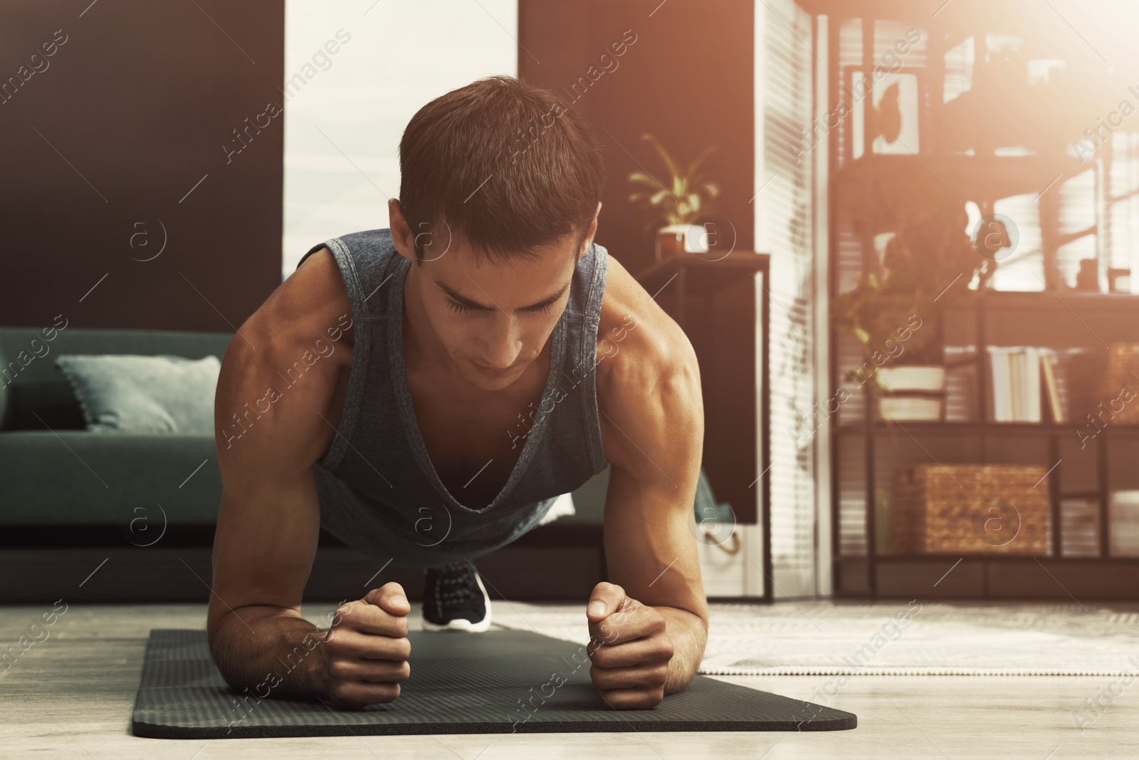 Sporty man doing plank exercise on fitness mat at home Image of Sporty man doing plank exercise on fitness mat at home