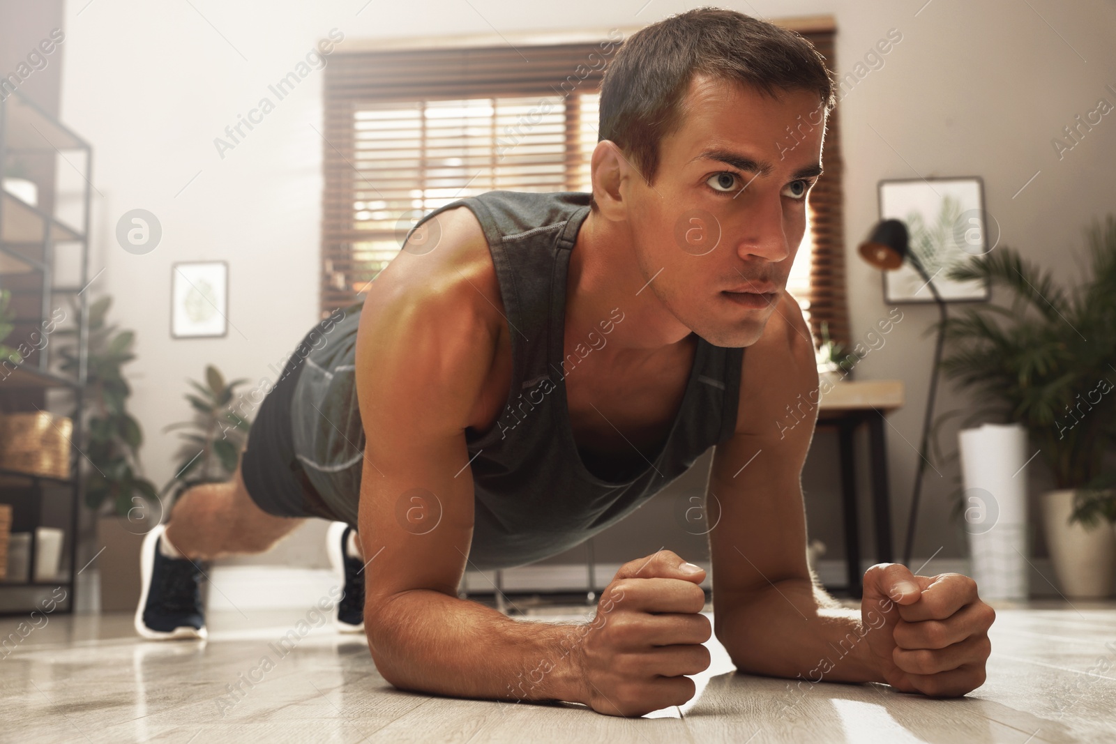 Sporty man doing plank exercise on floor at home Image of Sporty man doing plank exercise on floor at home