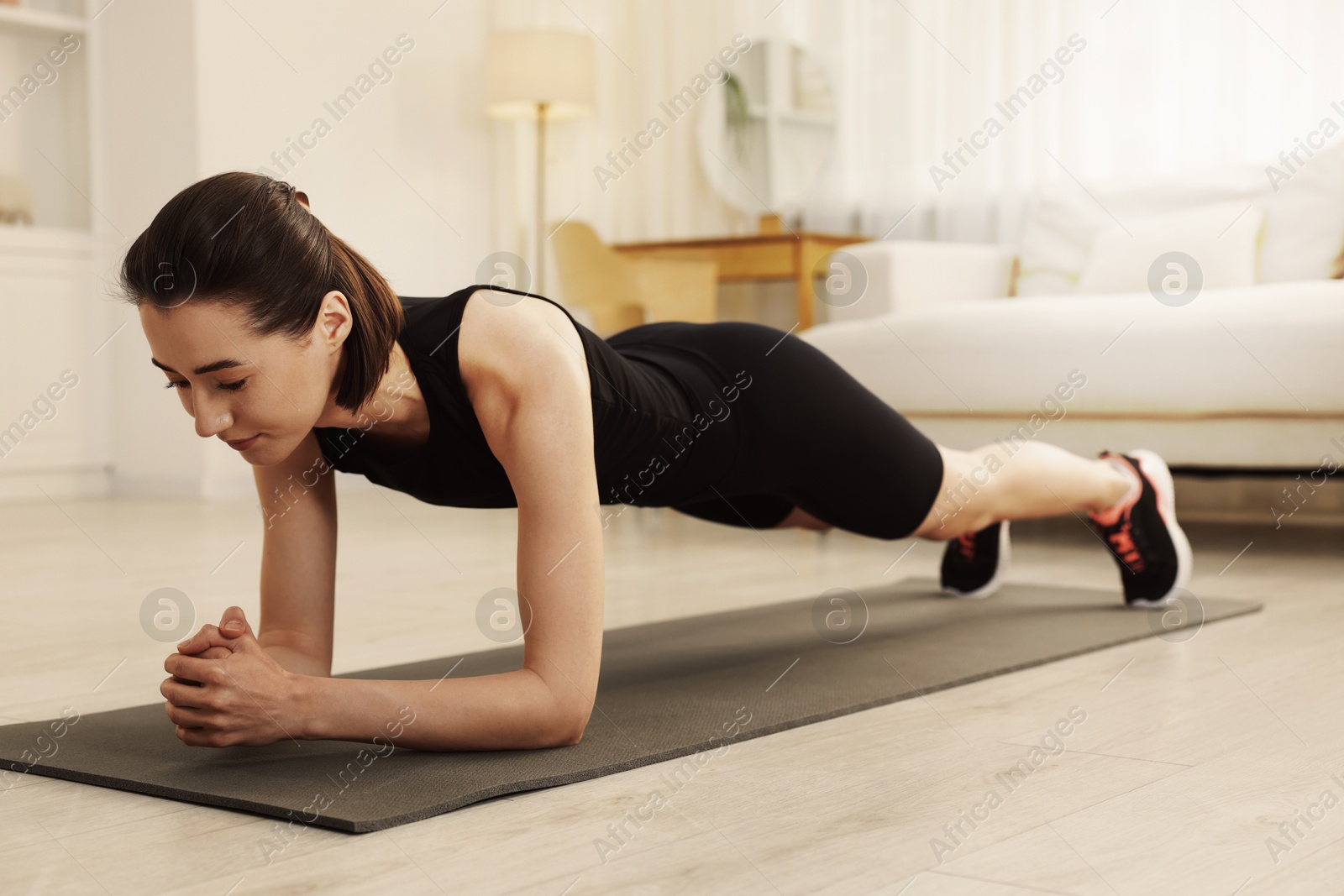 Young woman doing plank exercise on fitness mat at home. Sport and healthy lifestyle Image of Young woman doing plank exercise on fitness mat at home. Sport and healthy lifestyle
