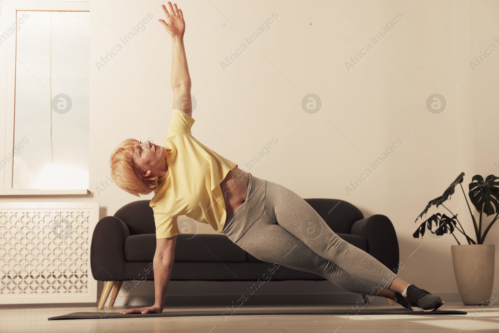 Woman doing side plank exercise on fitness mat at home. Sport and healthy lifestyle Image of Woman doing side plank exercise on fitness mat at home. Sport and healthy lifestyle