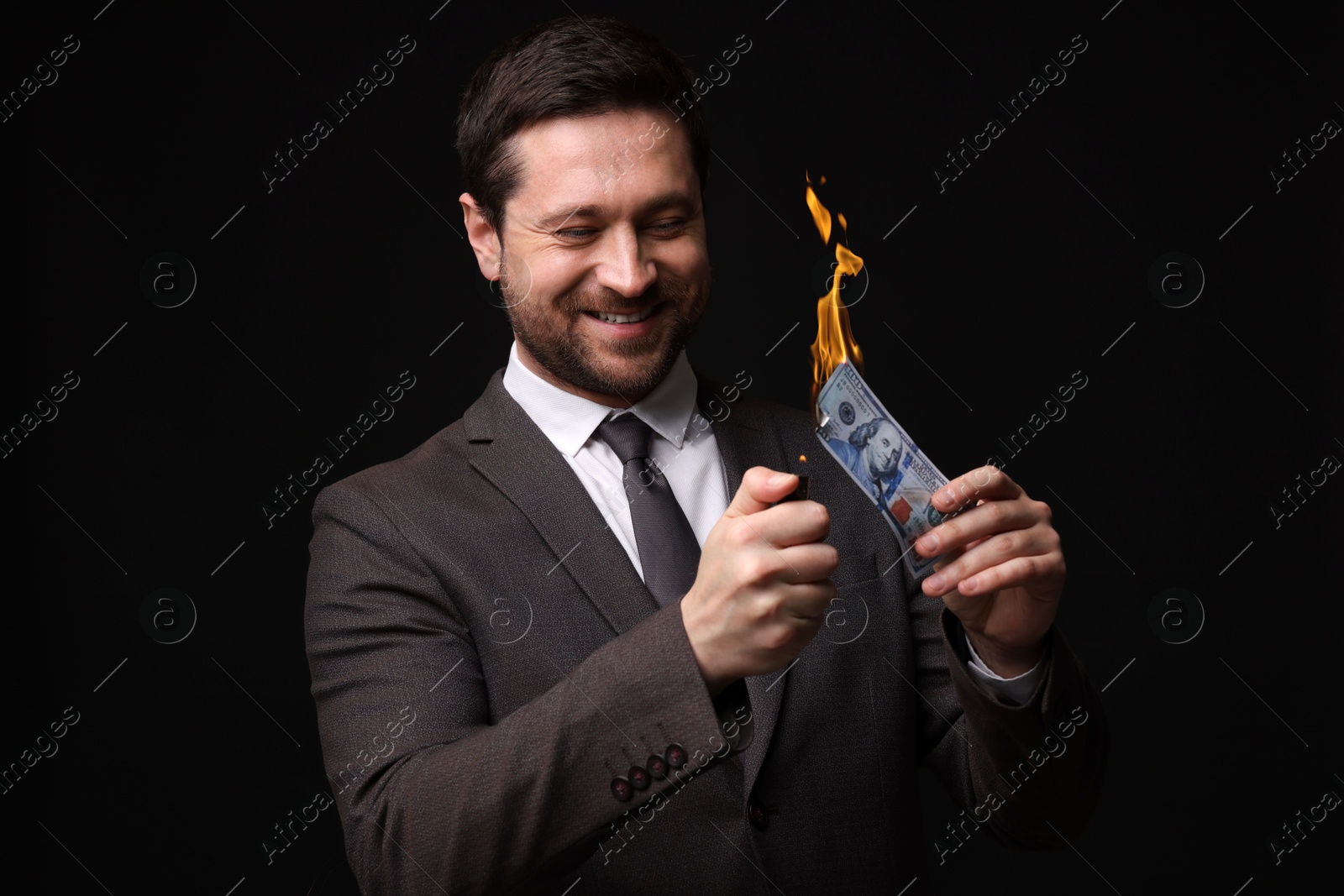 Greedy businessman burning dollar banknote with lighter on black background Image of Greedy businessman burning dollar banknote with lighter on black background