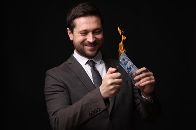 Image of Greedy businessman burning dollar banknote with lighter on black background
