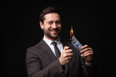 Image of Greedy businessman burning dollar banknote with lighter on black background
